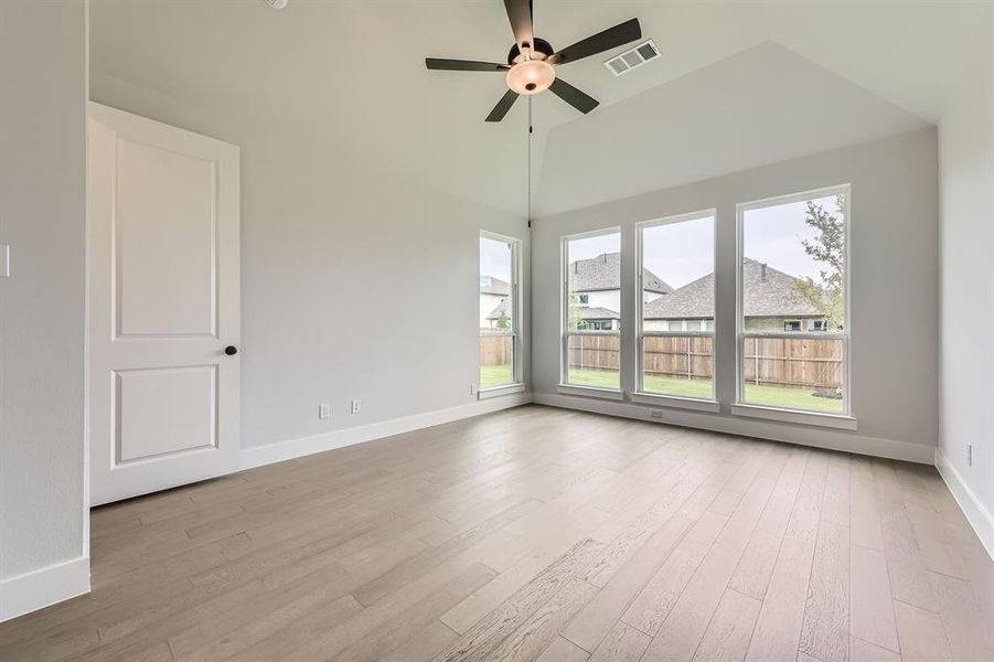 Unfurnished room featuring plenty of natural light, wood finished floors, a ceiling fan, baseboards, and lofted ceiling