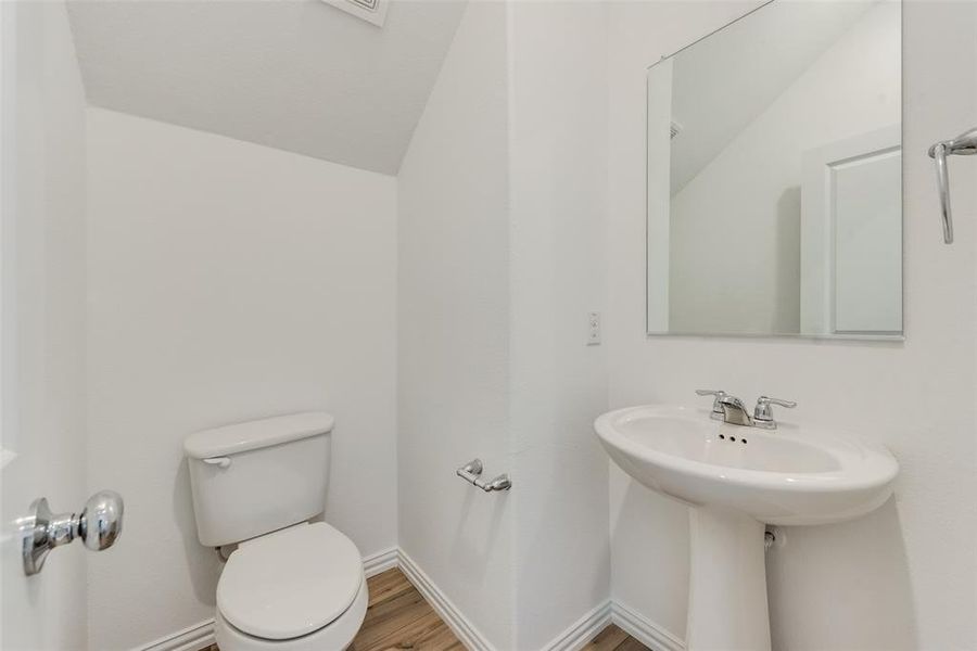 Bathroom featuring toilet, hardwood / wood-style flooring, and vaulted ceiling