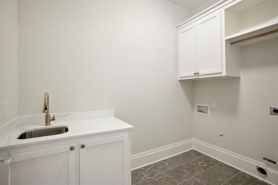 Laundry room has a sink upper hanging rod and storage.