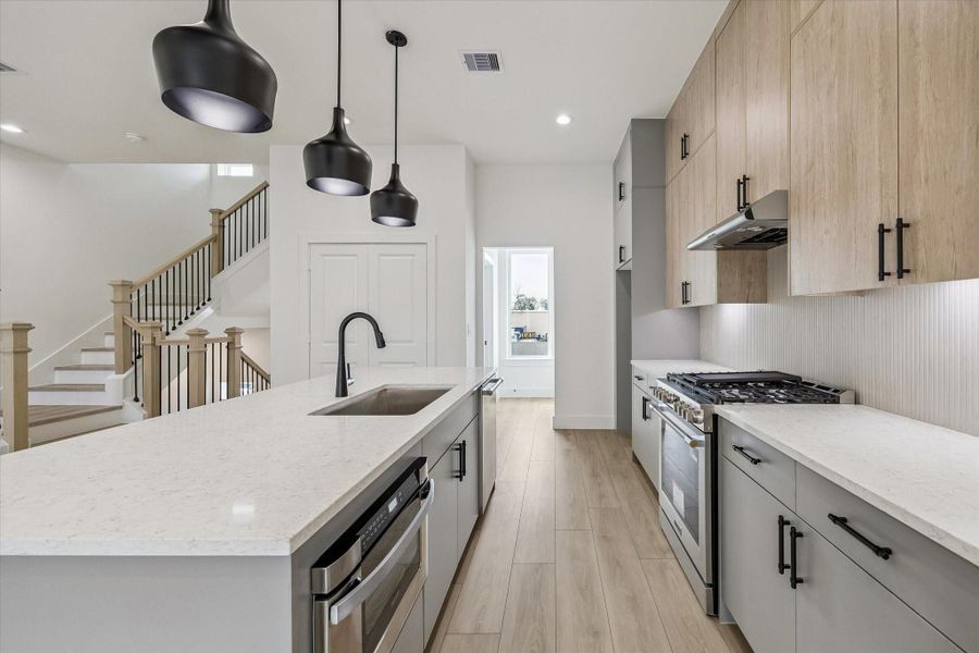 Functional kitchen workspace with gas range, vent hood, and extended counters Functional kitchen workspace with gas range, vent hood, and extended counters