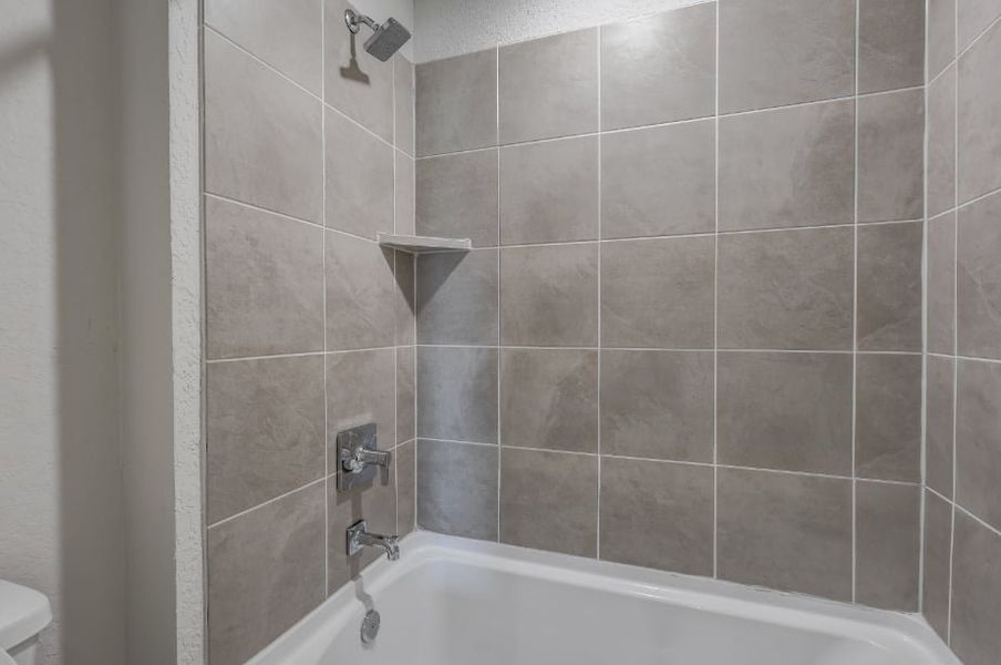 A bathtub with a tile wall.