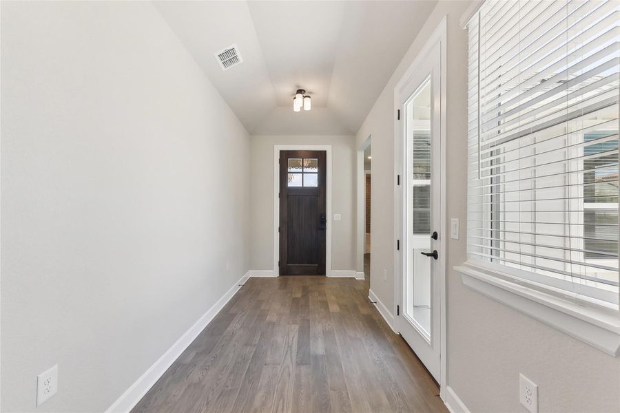 Entryway with dark wood-style floors, lofted ceiling, and baseboards Entryway with dark wood-style floors, lofted ceiling, and baseboards