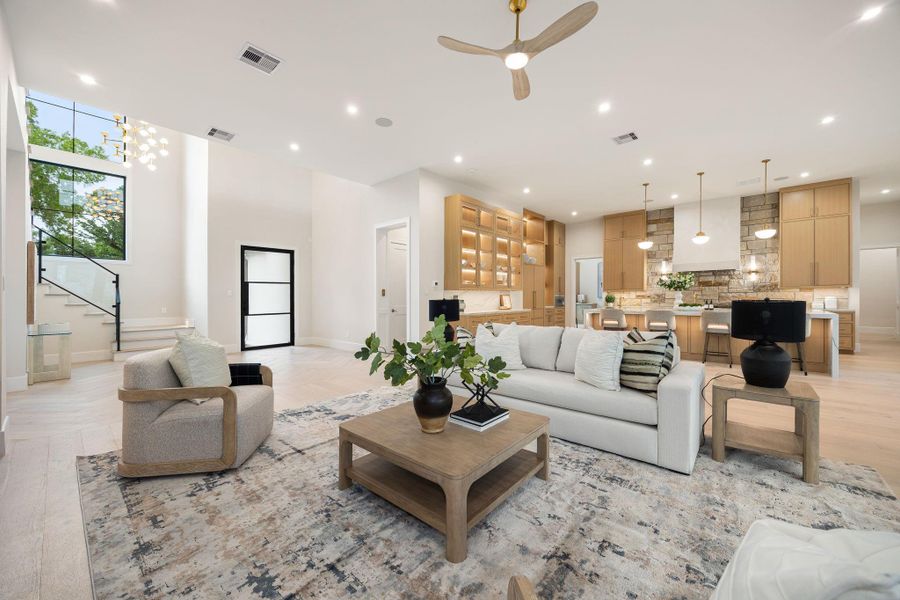 A beautifully connected living space that transitions effortlessly into the kitchen, framed by custom cabinetry and warm wood tones that carry throughout the home . The generous island anchors the room, while layered lighting and thoughtful detailing add depth and character. Open sightlines and balanced proportions create a natural flow, making the entire space feel both expansive and welcoming.