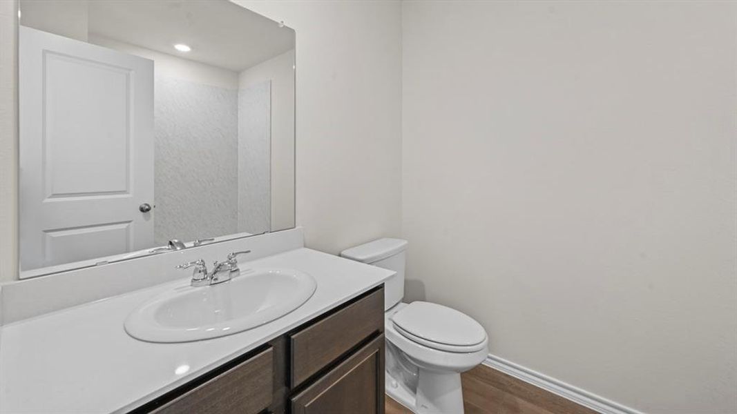 Half bath with vanity and dark wood-type flooring