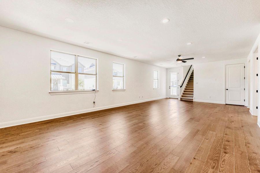 Unfurnished living room with light wood-type flooring, a ceiling fan, and a textured ceiling Unfurnished living room with light wood-type flooring, a ceiling fan, and a textured ceiling