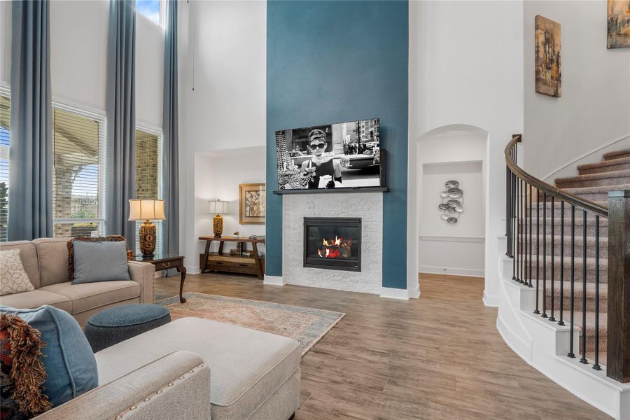 Living room featuring built in features, a high ceiling, a glass covered fireplace, wood finished floors, and stairway Living room featuring built in features, a high ceiling, a glass covered fireplace, wood finished floors, and stairway