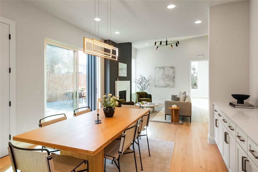 Dining area with a large fireplace, visible vents, light wood-style flooring, and recessed lighting