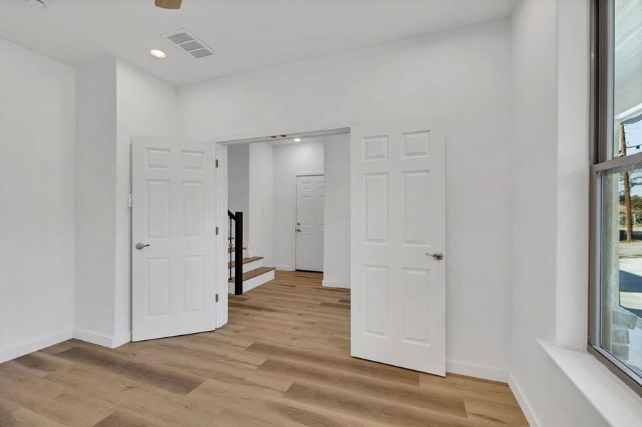 Spare room featuring light wood-type flooring, stairway, and recessed lighting