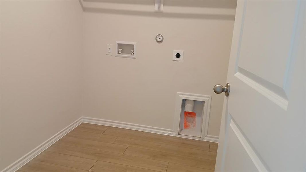 Dedicated utility space featuring light wood-finish flooring, white baseboards, and neutral wall paint Dedicated utility space featuring light wood-finish flooring, white baseboards, and neutral wall paint