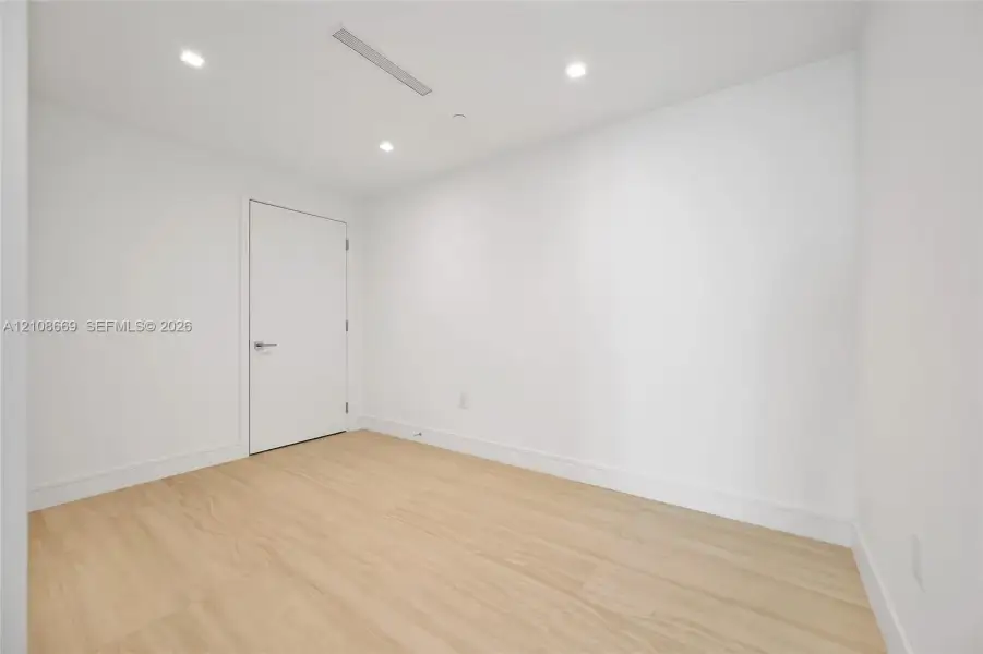 Neutral-toned wood-finish flooring, recessed ceiling lighting, and crisp white wall finishes