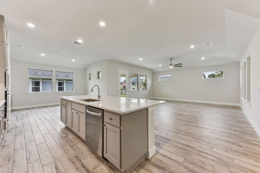 Kitchen with open floor plan, a center island with sink, light wood-type flooring, stainless steel dishwasher, and recessed lighting