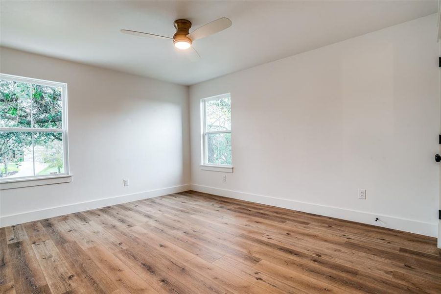 Spare room featuring wood-type flooring, plenty of natural light, and ceiling fan