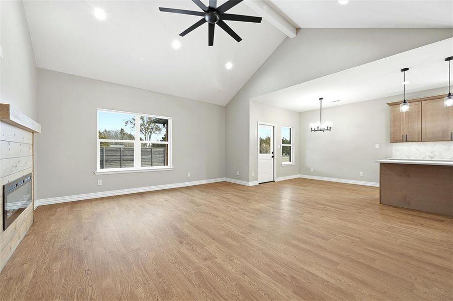 Unfurnished living room with a ceiling fan, light wood-style floors, a glass covered fireplace, and hanging lights Unfurnished living room with a ceiling fan, light wood-style floors, a glass covered fireplace, and hanging lights