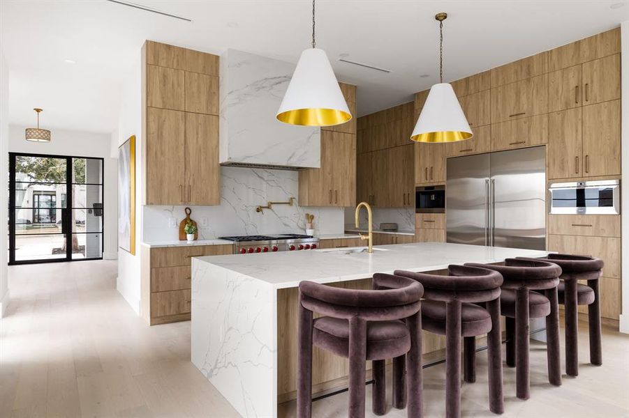 Kitchen featuring stainless steel appliances, modern cabinets, a sink, and decorative light fixtures