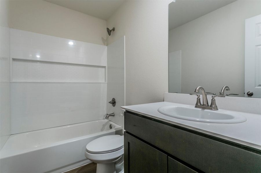 Full bath featuring shower / washtub combination, wood finished floors, vanity, and toilet Full bath featuring shower / washtub combination, wood finished floors, vanity, and toilet