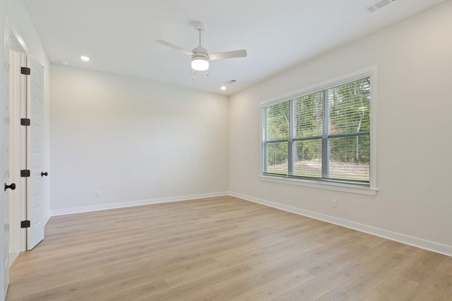 Spacious room featuring wood-finish flooring, a ceiling fan, recessed lighting, and a large window with blinds