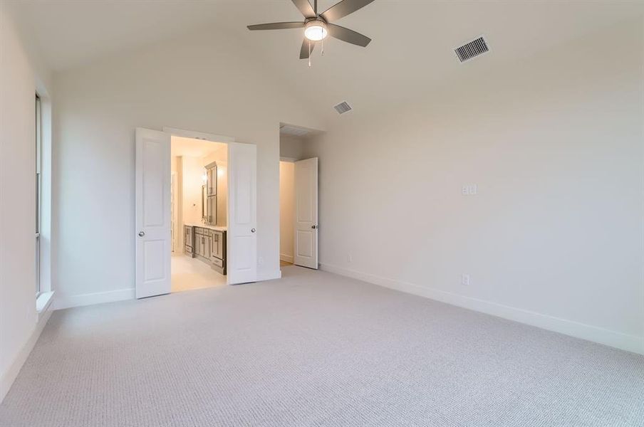 Unfurnished bedroom featuring light carpet, ensuite bath, high vaulted ceiling, and ceiling fan