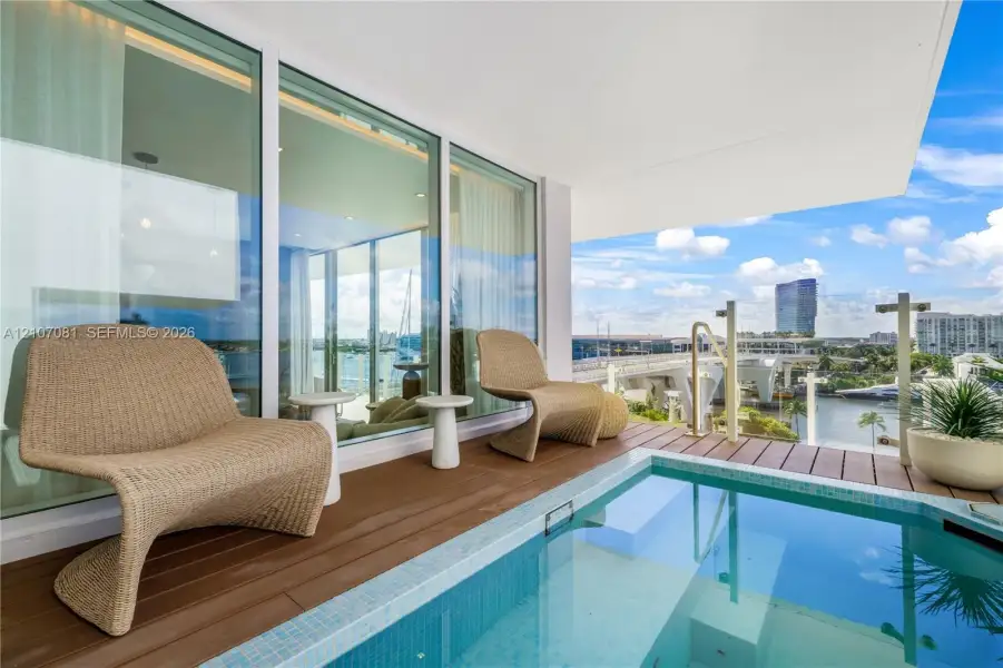 Covered balcony featuring wood-finish decking, a built-in plunge pool with tiled lining, floor-to-ceiling glass panel walls, and a glass-paneled railing Covered balcony featuring wood-finish decking, a built-in plunge pool with tiled lining, floor-to-ceiling glass panel walls, and a glass-paneled railing