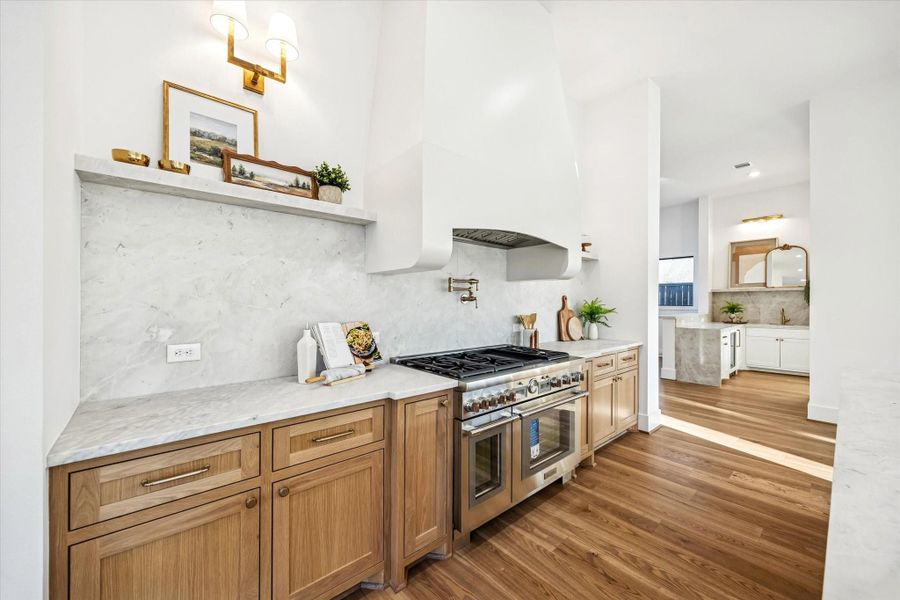 Dedicated cooking wall features a professional grade range, pot filler, and full height stone backsplash for a clean, high performance workspace. Surrounding cabinetry and counters provide ample room for prep while maintaining separation from entertaining zones. **Previous build by Arch Angelo** Dedicated cooking wall features a professional grade range, pot filler, and full height stone backsplash for a clean, high performance workspace. Surrounding cabinetry and counters provide ample room for prep while maintaining separation from entertaining zones. **Previous build by Arch Angelo**