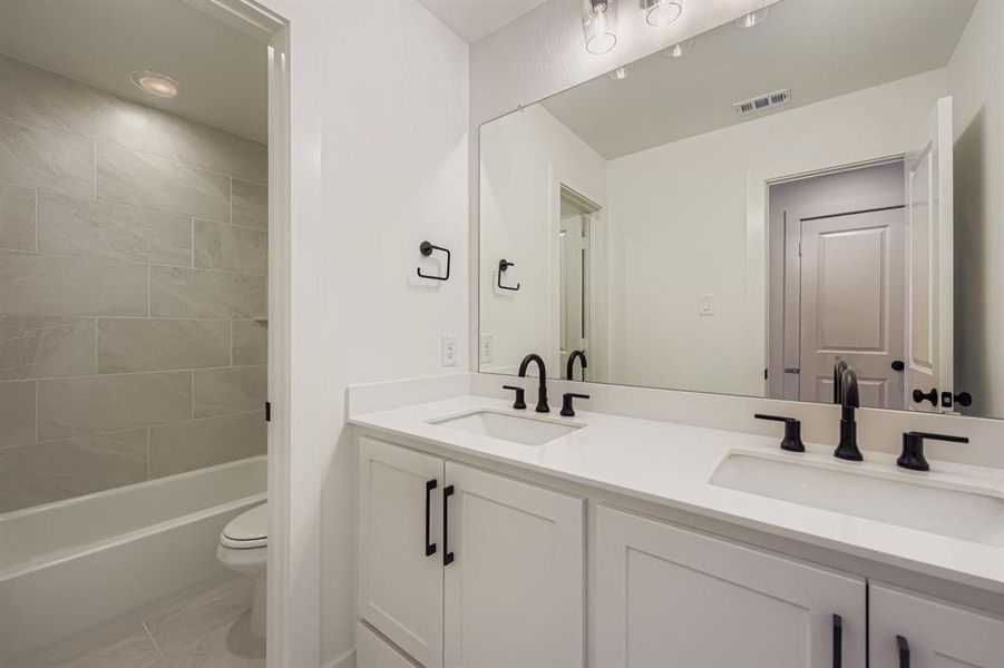 Bathroom featuring double vanity and bathtub / shower combination