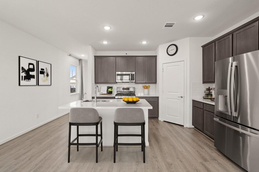 The heart of the home! This modern kitchen features elegant cabinetry, an island with seating, sleek stainless steel appliances, and recessed lighting—perfect for gathering and entertaining. *This photo has been virtually staged