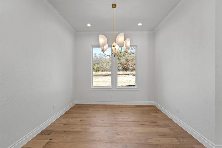 Unfurnished dining area featuring ornamental molding, light hardwood / wood-style floors, and a notable chandelier