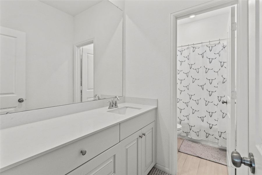 Bright, modern bathroom featuring a sleek vanity with ample counter space and a stylish shower curtain accent. Bright, modern bathroom featuring a sleek vanity with ample counter space and a stylish shower curtain accent.