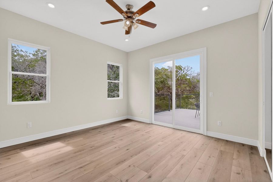 Sliding glass doors open from wood-floored interiors to a private elevated deck overlooking nature.