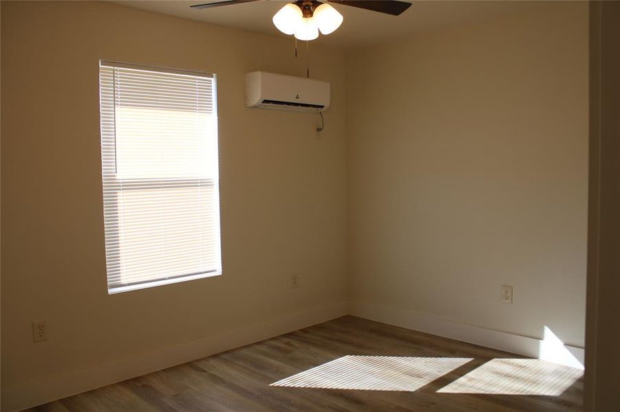 Spare room featuring wood finished floors, an AC wall unit, and ceiling fan