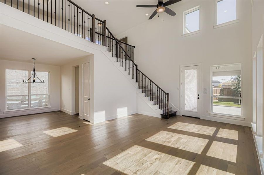 Foyer featuring light wood-style flooring, stairway, a high ceiling, a chandelier, and a ceiling fan Foyer featuring light wood-style flooring, stairway, a high ceiling, a chandelier, and a ceiling fan