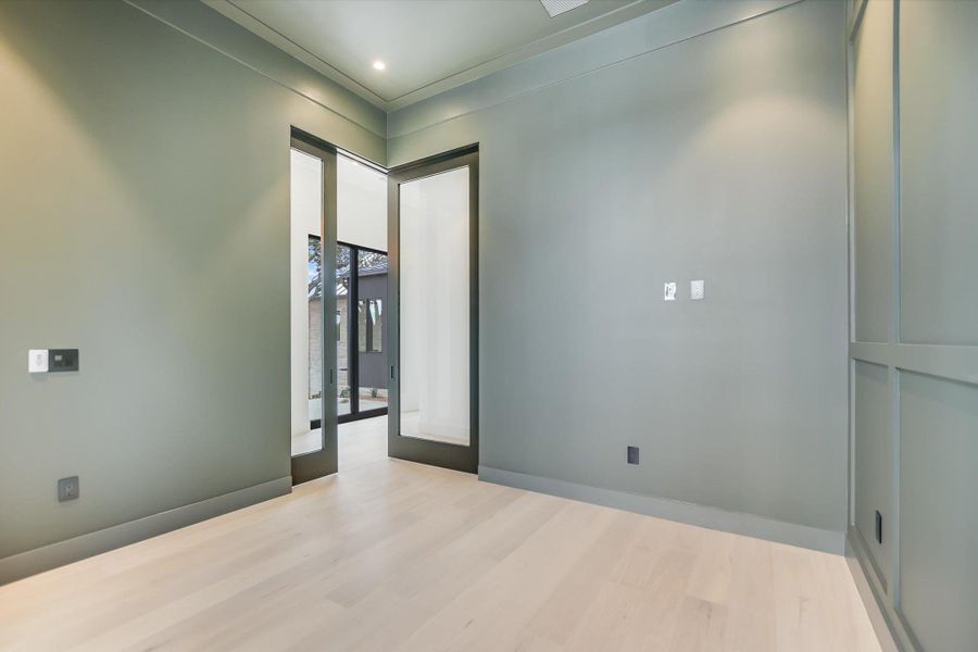 Recessed lighting illuminates the light wood flooring in this contemporary interior space.