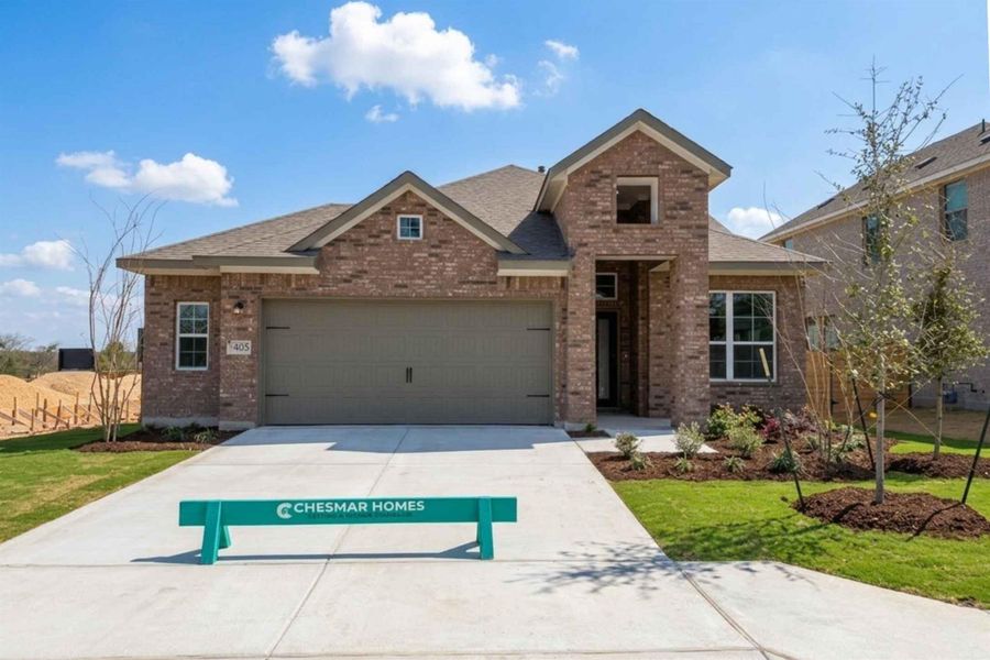 View of front of property featuring brick siding, a garage, driveway, and a front lawn