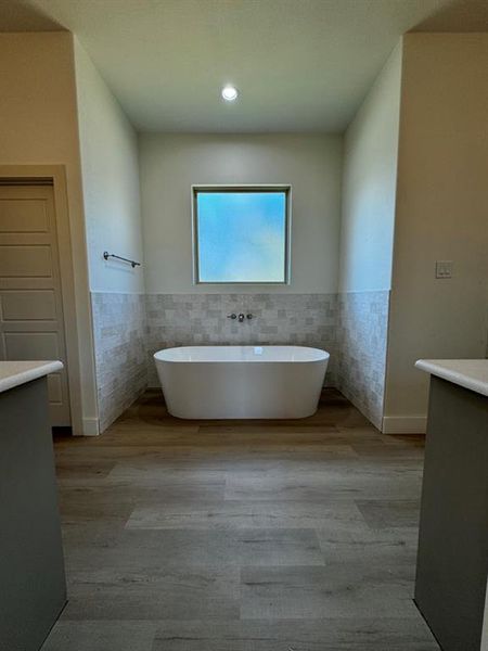 Bathroom with tile walls, vanity, and a bath