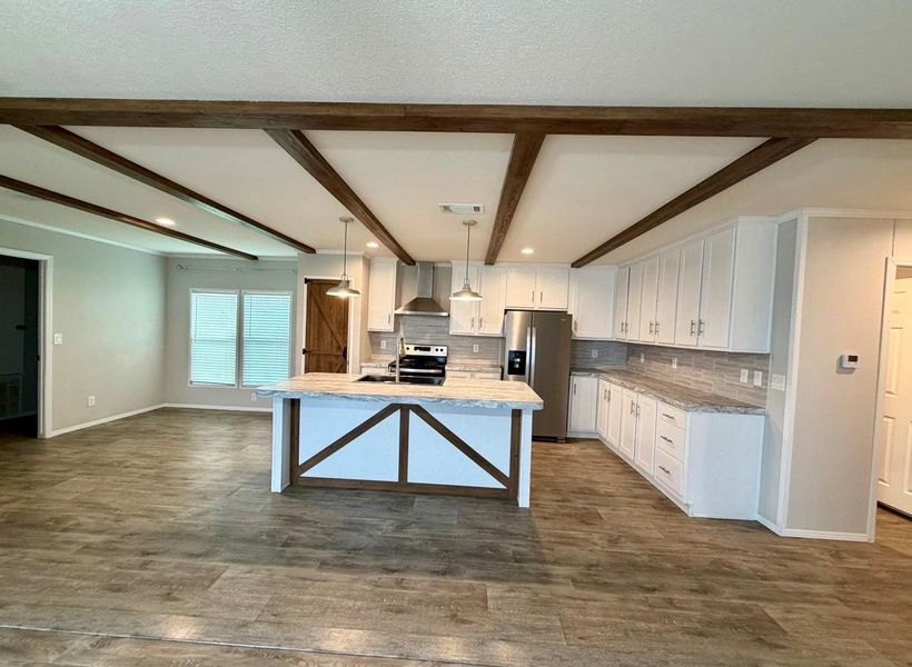 Kitchen featuring an island with built-in storage, white cabinetry, stainless steel appliances, and wood-finish flooring throughout