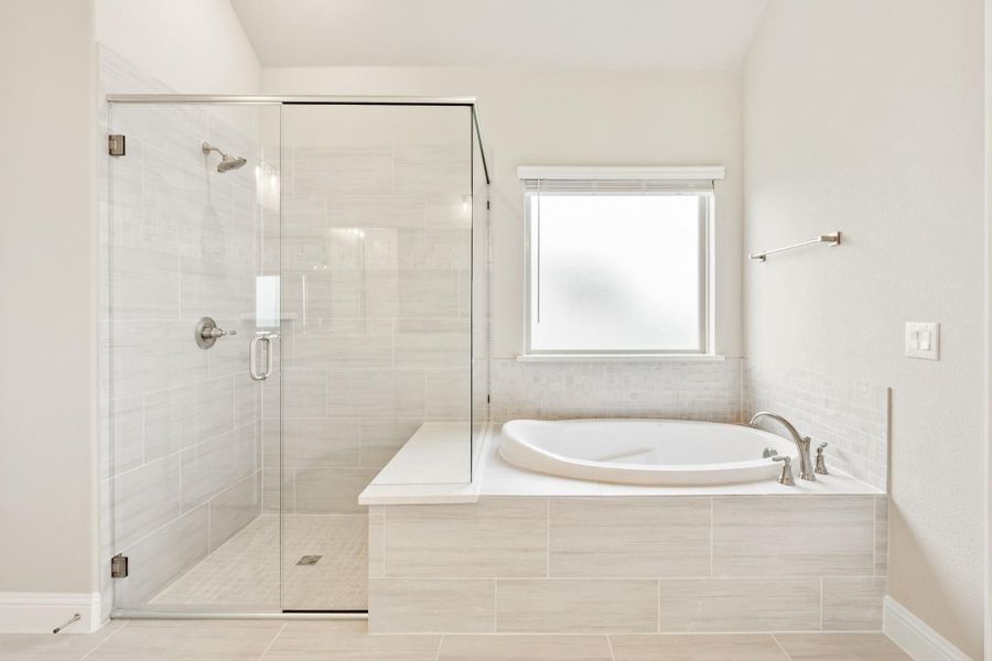 Bathroom with glass-enclosed walk-in shower and soaking tub with tile surround