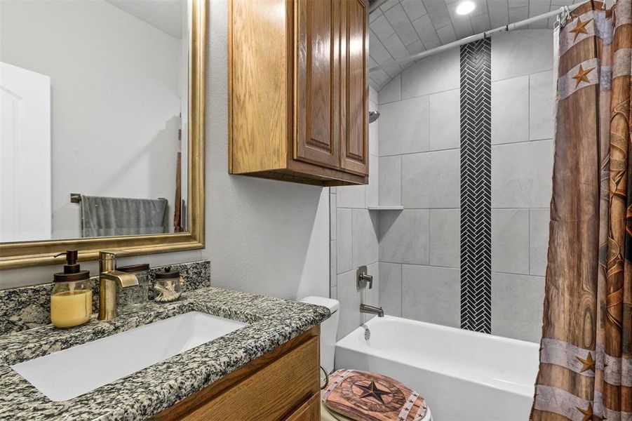 Full bathroom featuring vanity, vaulted ceiling, shower / bath combination with curtain, and toilet