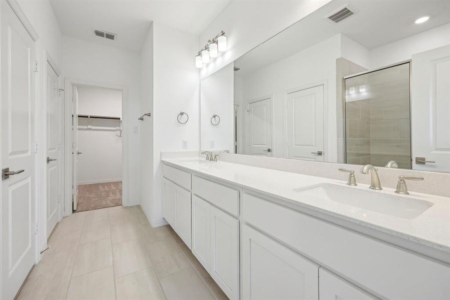 Primary Bathroom with tile patterned flooring, a shower with shower door, and vanity