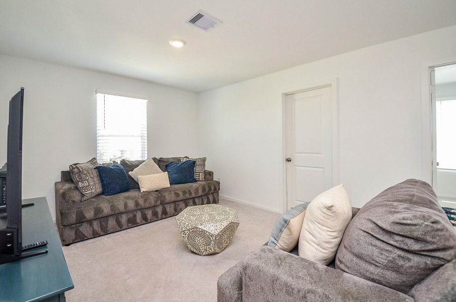 This is a modern two-story home with a stone exterior and gabled roof. It features a two-car garage and a neatly landscaped front yard. The house is surrounded by greenery, providing a tranquil setting.