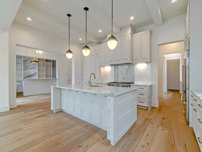 Bright and spacious kitchen with oversized island, custom cabinetry, marble backsplash, and high-end appliances.*Images depict previously completed homes by Roberson Building Group and are intended solely to showcase builder quality and craftsmanship.