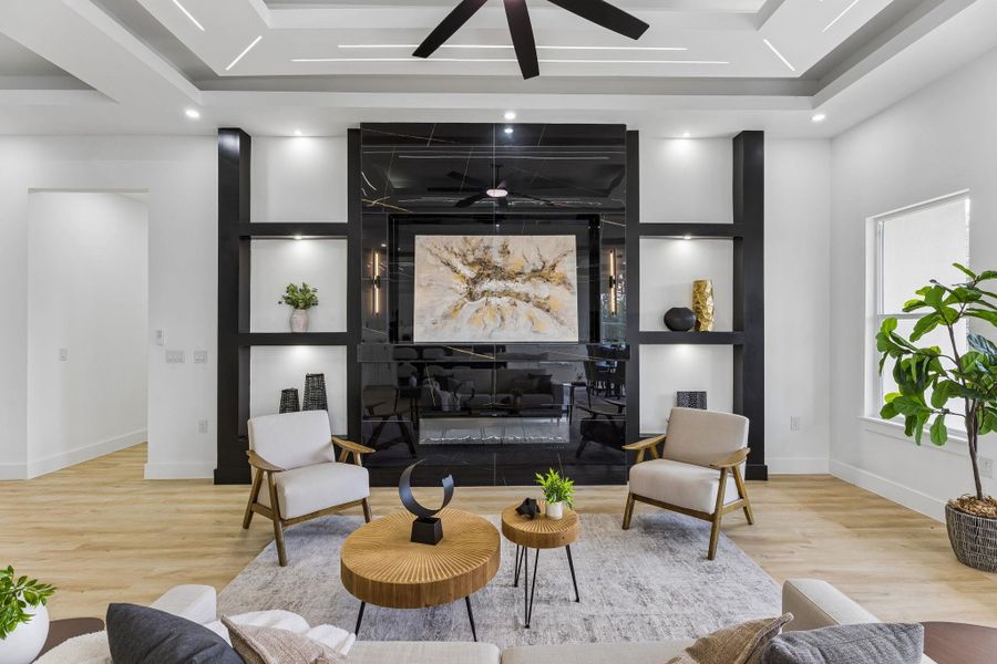 An architectural focal wall with built-ins frames a sleek fireplace under a tray ceiling.