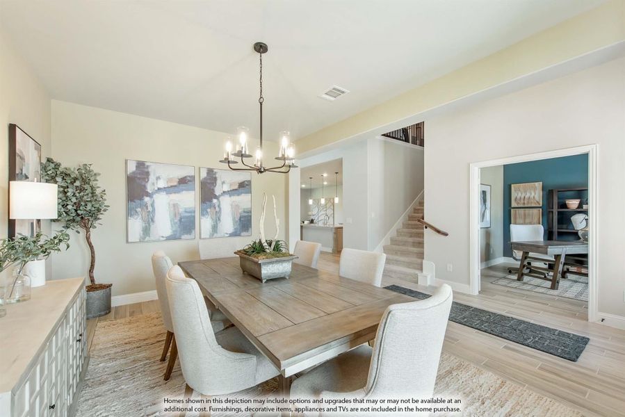 Dining room with wood table, upholstered chairs, chandelier, and light hardwood floors near staircase Dining room with wood table, upholstered chairs, chandelier, and light hardwood floors near staircase