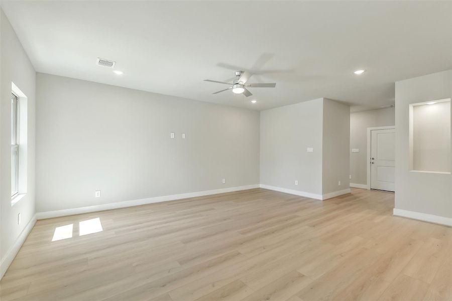Spacious living area with neutral tones, recessed lighting and wood flooring creating a warm and modern feel.