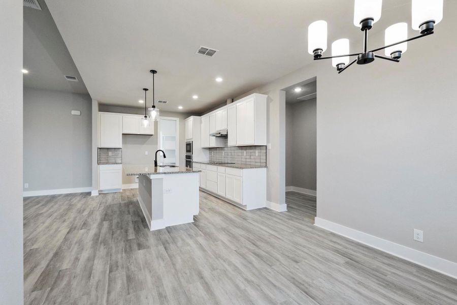 Kitchen featuring white cabinetry, hanging light fixtures, a kitchen island with sink, backsplash, and recessed lighting