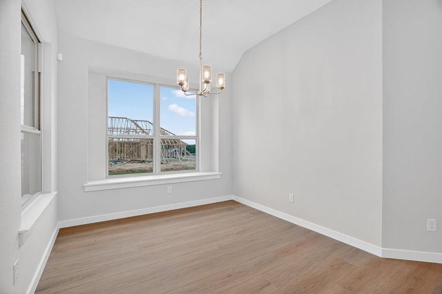 Open room featuring wood-finish flooring, white baseboards, and a contemporary chandelier