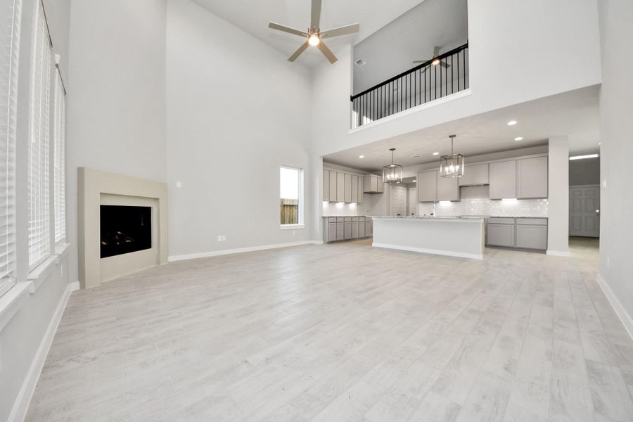 Family room flooded with natural light through the expansive windows.  The premium tile flooring adds a touch of luxury to the space, creating the perfect setting for relaxing moments and cherished gatherings with loved ones. Sample photo of completed home with similar floor plan. Actual colors and selections may vary.