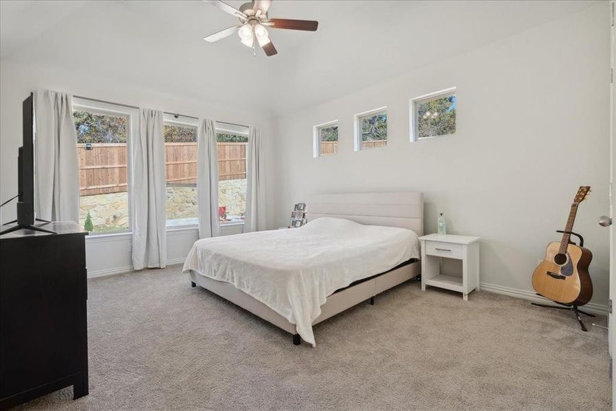 Carpeted bedroom with multiple windows and ceiling fan