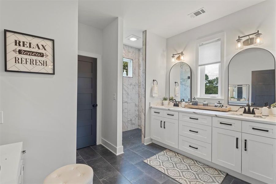 Spa-inspired primary bath featuring dual vanities, designer lighting, sleek black hardware, and a spacious walk-in shower with refined tilework—creating a polished, luxury retreat with modern country elegance.