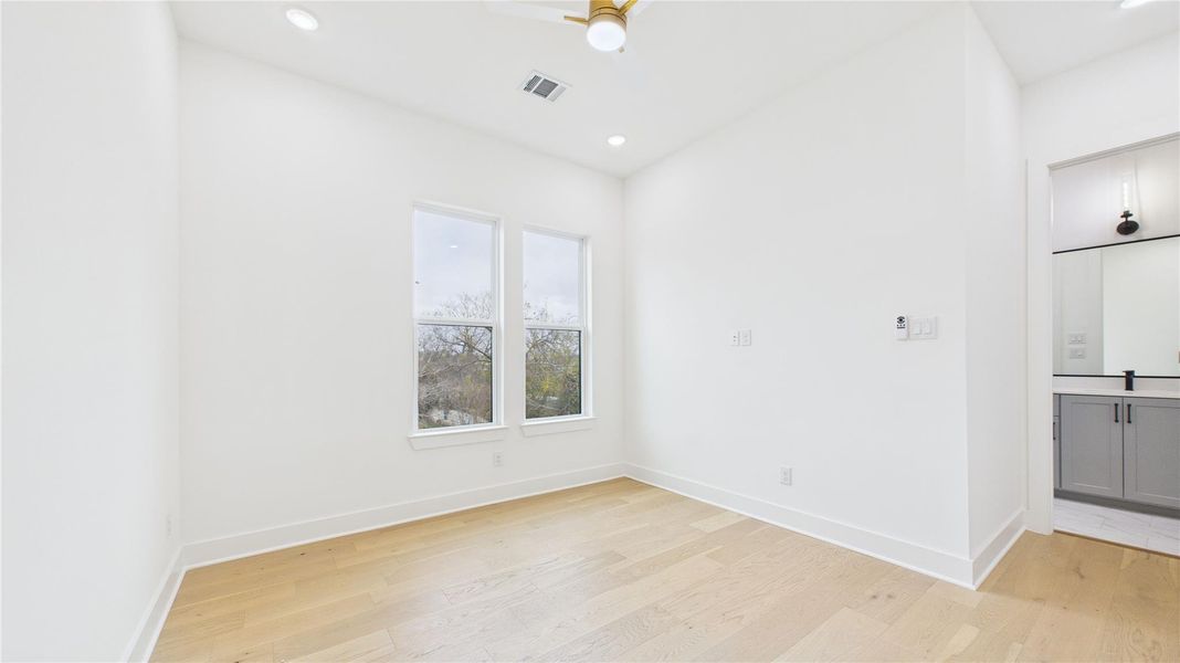 Two windows for natural light and an adjacent bathroom with modern fixtures.