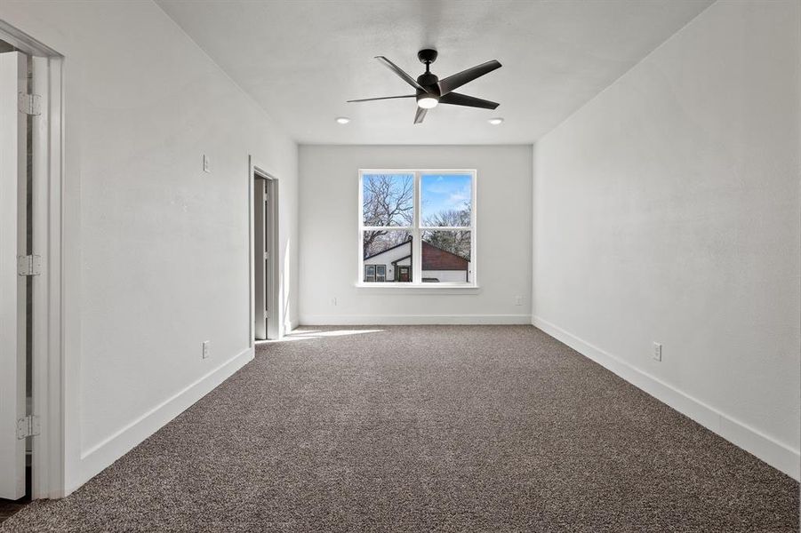 Carpeted empty room featuring ceiling fan