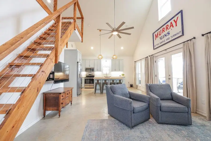Living area featuring high vaulted ceiling, plenty of natural light, finished concrete flooring, french doors, and ceiling fan